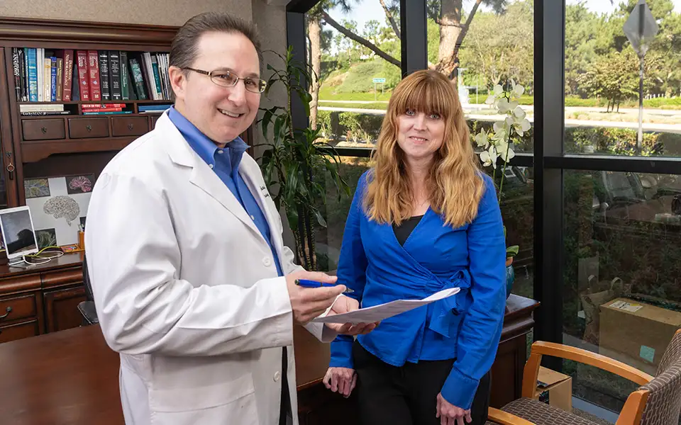 Dr. Kenneth Martinez stands in his office discussing a patient with Allison Smith