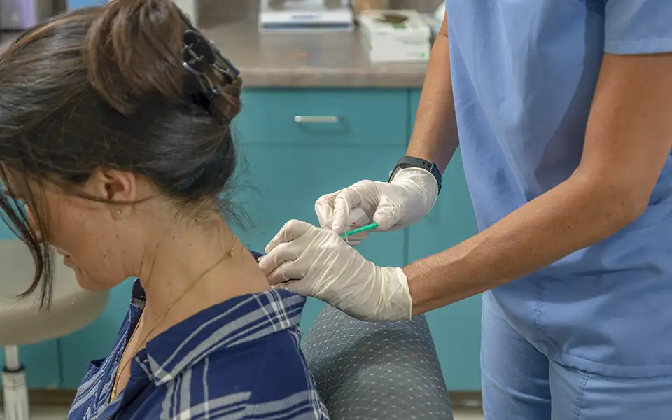 Wendy Reulman gives a patient a botulinum toxin injection at the base of the neck