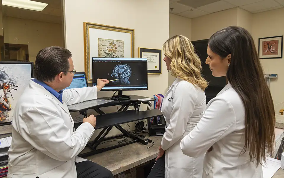 Dr. Kenneth Martinez reviews head and neck X-rays with Wendy Reulman and Elizabeth Rodriguez